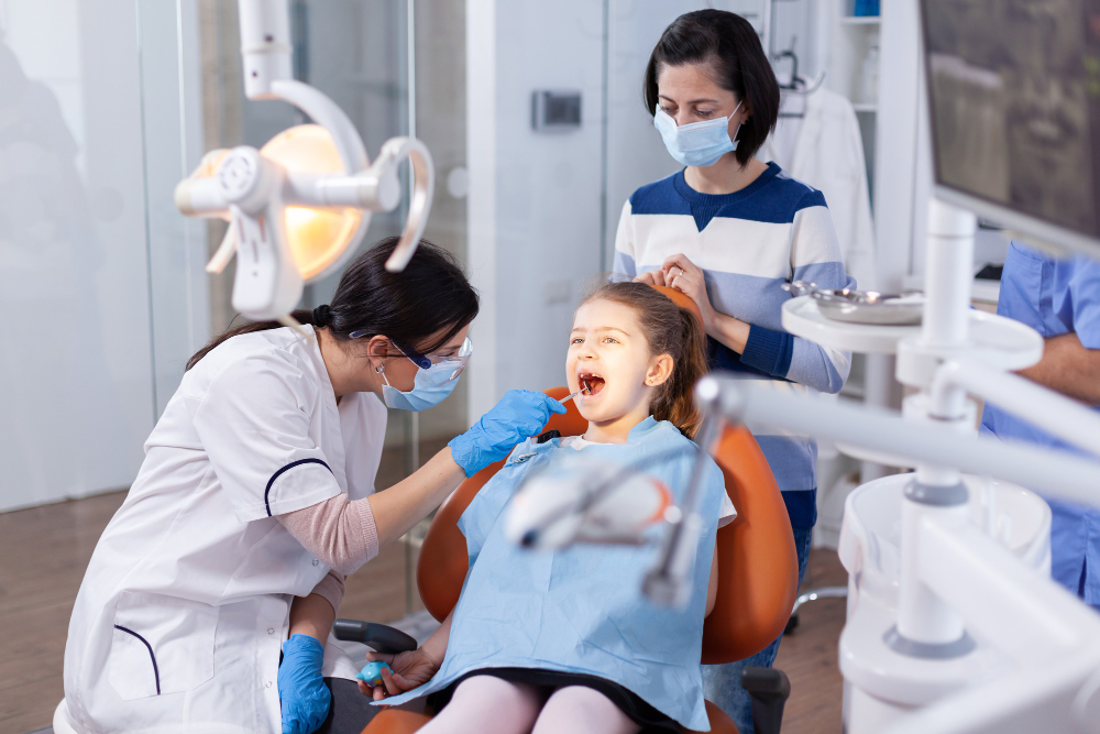 angled mirror used by dentist doctor little girl with mouth open dental office dentistry specialist during child cavity consultation stomatology office using modern technology